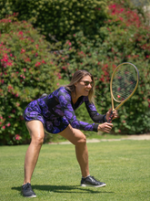 Load image into Gallery viewer, The Angelina Dress is modern yet classy. This style is in our very limited Purple Pansy print, with a flattering v-neck neckline. This soft, silky, and sexy tennis dress has an empire waist and a feminine skirt.